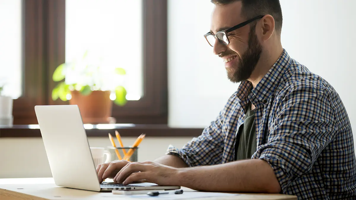 Man typing on laptop in office setting.